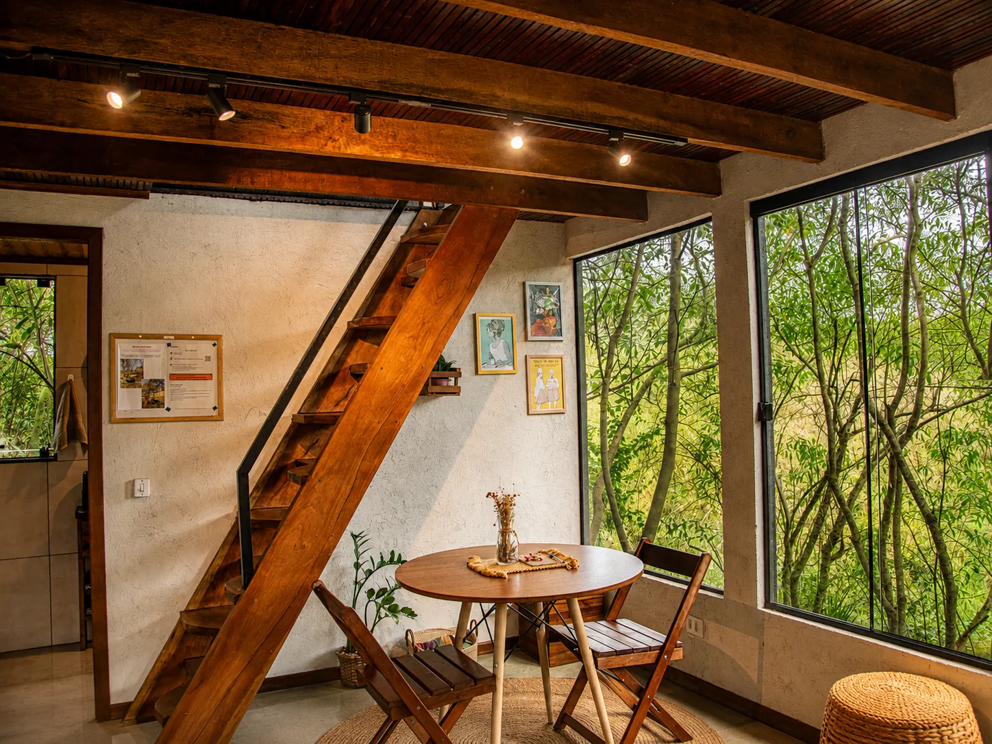 Coletivo Bambu a Pique - Cabana Vibe, sala com escada, mesa redonda e janelas para o bosque